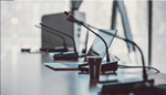 A conference room featuring several microphones and laptops arranged for a meeting.