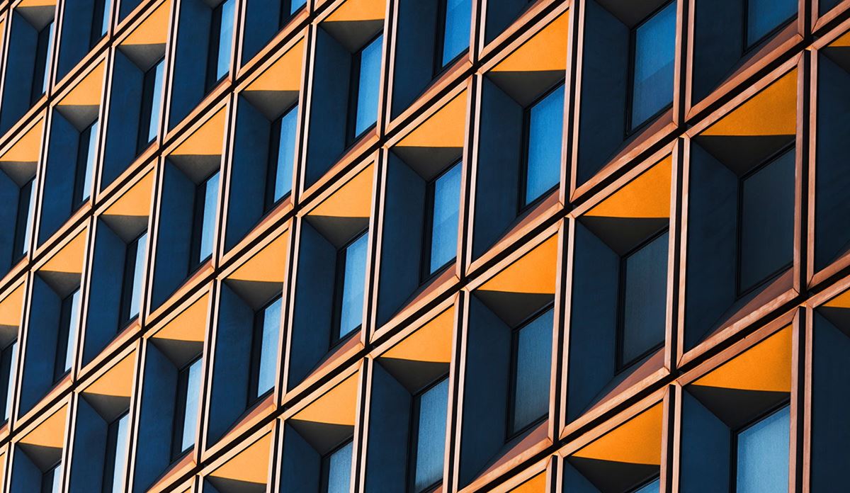 Modern building facade featuring repeating geometric windows patterns in blue and yellow tones