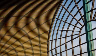 Modern architectural glass atrium with arched metal framework.
